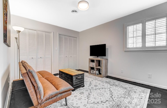 living room with visible vents, baseboards, and wood finished floors