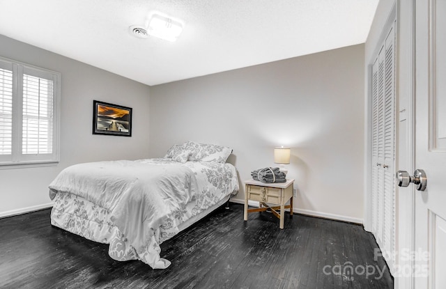 bedroom featuring dark wood-style floors, a closet, and baseboards