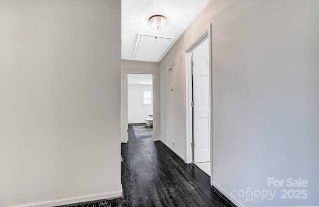 hall with dark wood-style floors, attic access, and baseboards