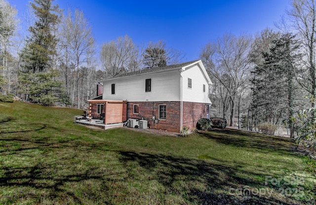 rear view of property with a yard, a patio area, central AC, and brick siding