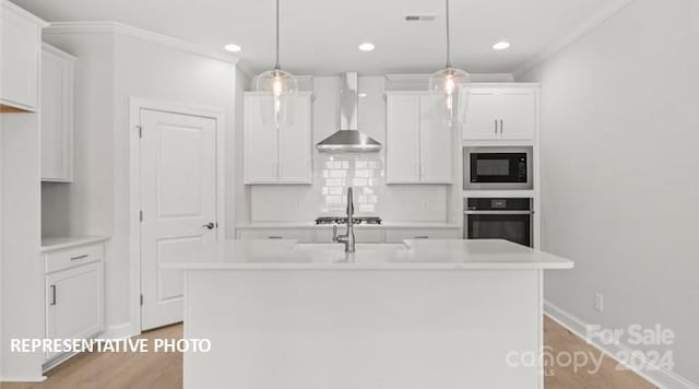 kitchen with wall chimney exhaust hood, built in microwave, pendant lighting, and oven