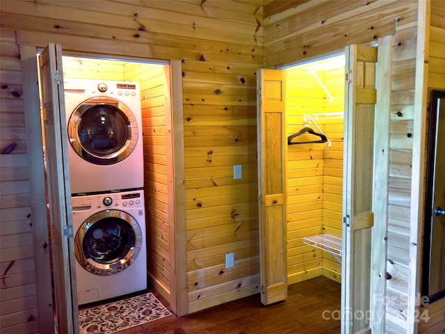 washroom with stacked washing maching and dryer, dark wood-type flooring, and wooden walls