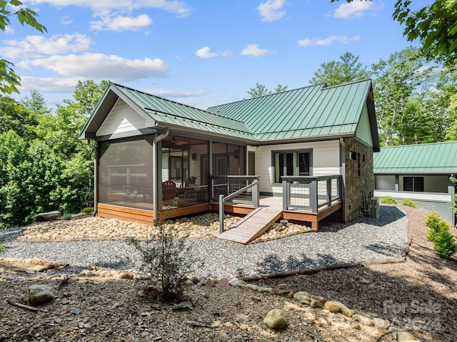 back of property with a wooden deck and a sunroom