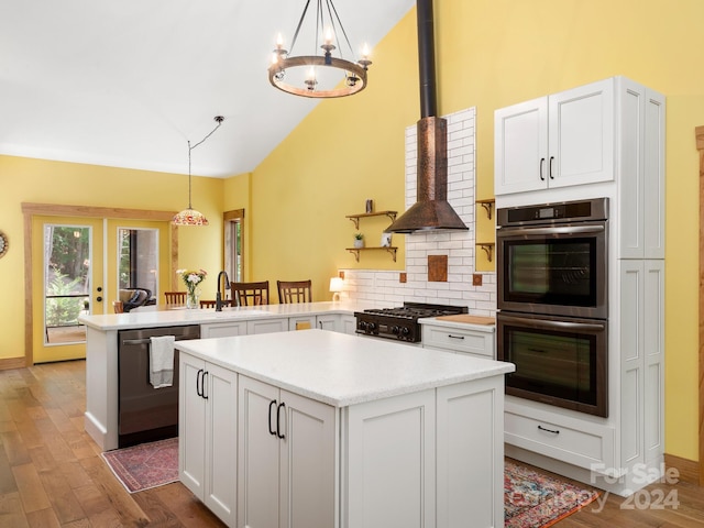 kitchen with white cabinets, kitchen peninsula, appliances with stainless steel finishes, and pendant lighting