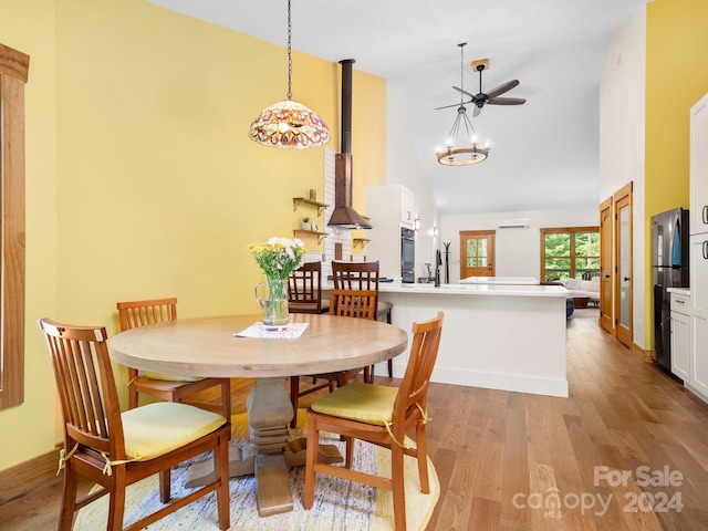 dining space with light hardwood / wood-style floors, an AC wall unit, and high vaulted ceiling