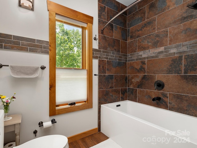 bathroom featuring toilet, tiled shower / bath combo, and hardwood / wood-style floors