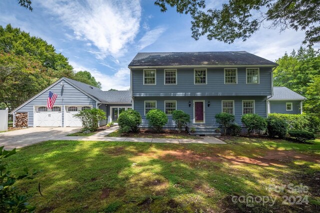 colonial home with a garage and a front lawn