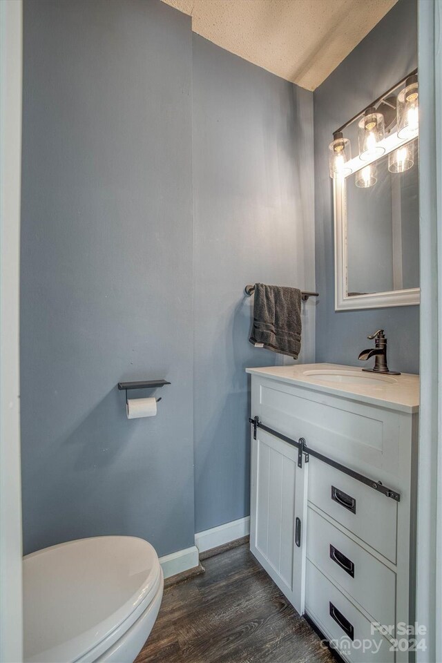 bathroom featuring vanity, a textured ceiling, wood-type flooring, and toilet