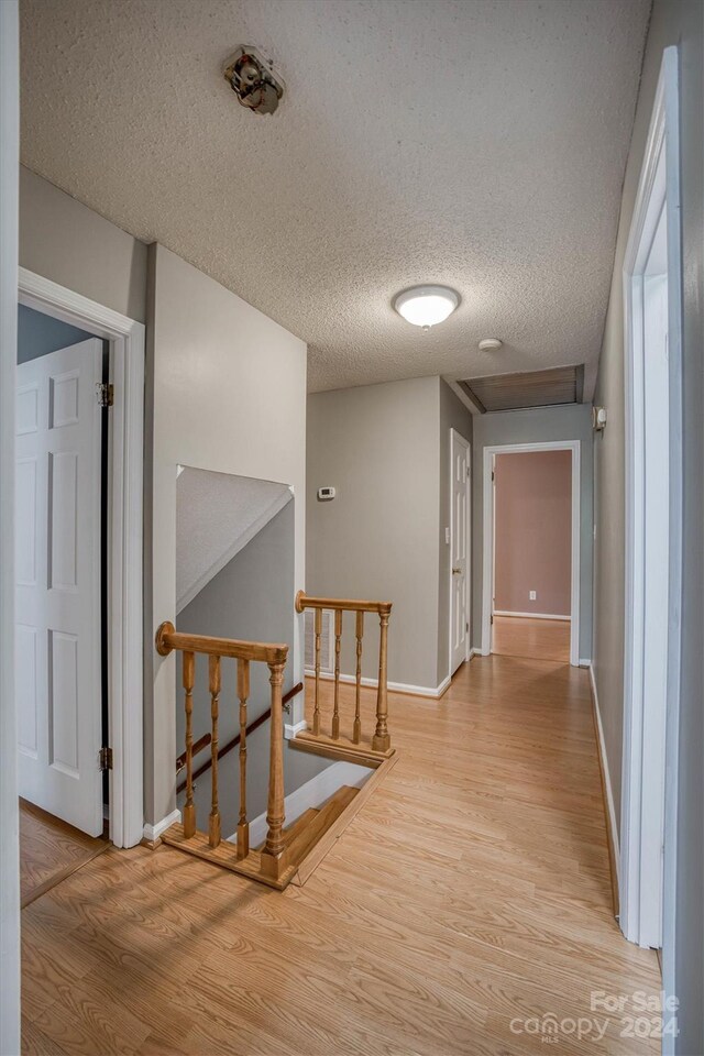 corridor with light hardwood / wood-style flooring and a textured ceiling