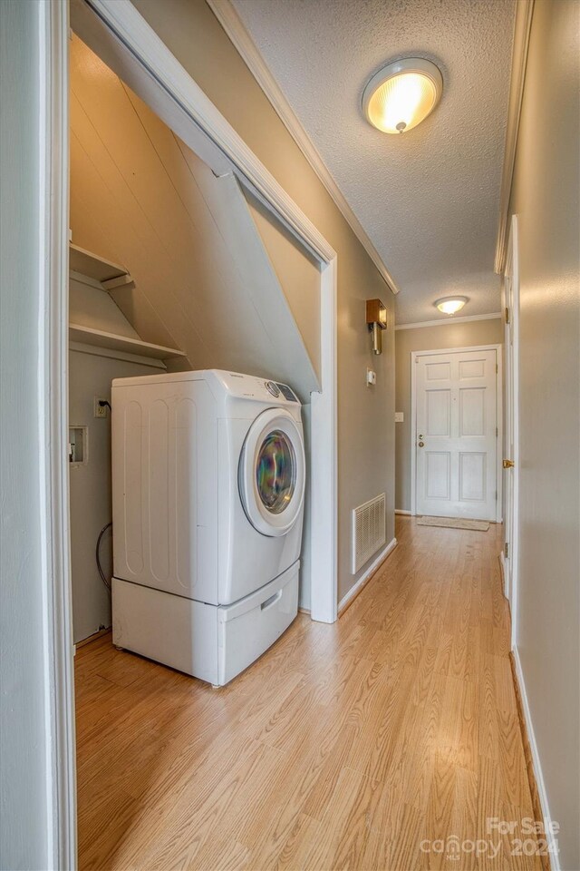 laundry area featuring washer / dryer, light hardwood / wood-style floors, crown molding, and a textured ceiling