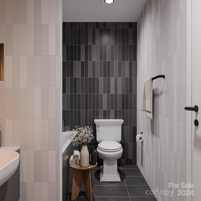 bathroom with toilet, tile patterned flooring, and tile walls