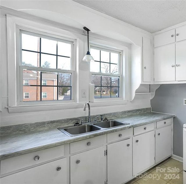 kitchen featuring light tile patterned floors, white cabinetry, hanging light fixtures, a textured ceiling, and sink