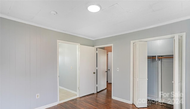 unfurnished bedroom with a closet, dark hardwood / wood-style flooring, and ornamental molding