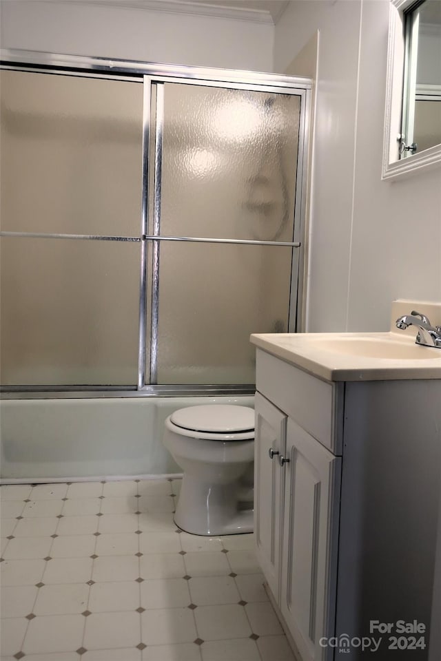 full bathroom with combined bath / shower with glass door, vanity, and toilet