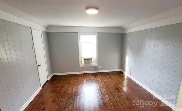 unfurnished room with vaulted ceiling, dark hardwood / wood-style flooring, cooling unit, and wooden walls