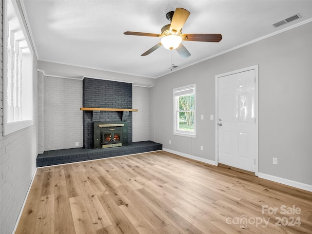 unfurnished living room featuring a fireplace, brick wall, crown molding, and light hardwood / wood-style floors