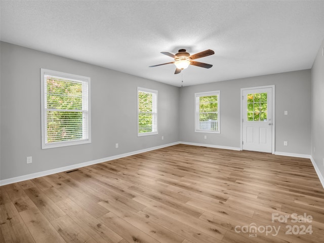 unfurnished room with ceiling fan, light wood-type flooring, and a textured ceiling