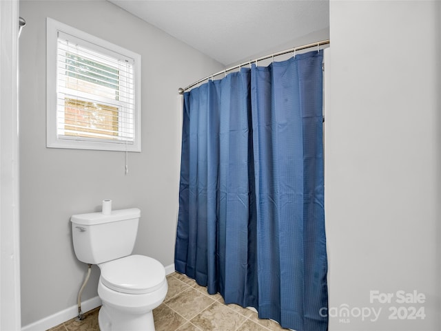 bathroom featuring toilet, tile patterned floors, and curtained shower