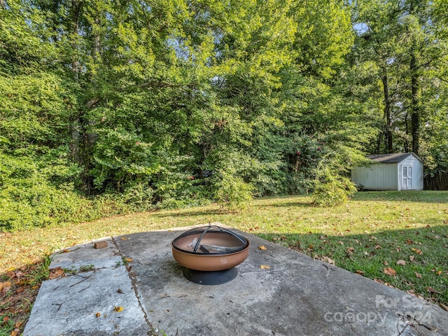 view of yard featuring an outdoor fire pit, a storage shed, and a patio