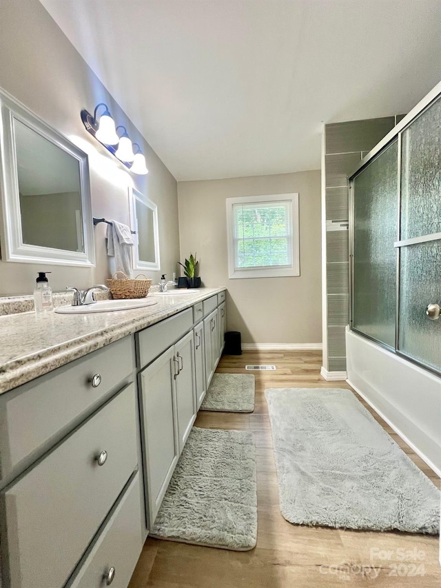 bathroom featuring vanity, wood-type flooring, and enclosed tub / shower combo