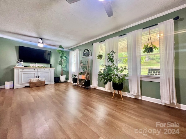 unfurnished living room featuring a textured ceiling, ceiling fan, crown molding, and light hardwood / wood-style floors