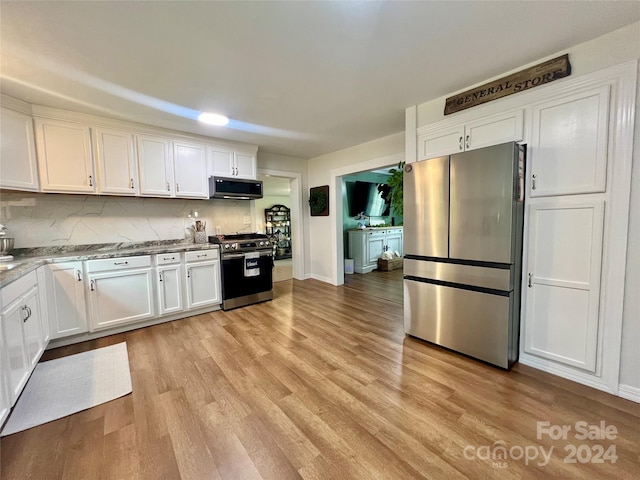 kitchen with white cabinets, stainless steel appliances, washing machine and clothes dryer, decorative backsplash, and light hardwood / wood-style floors