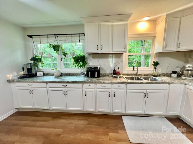 kitchen with decorative backsplash, light hardwood / wood-style flooring, white cabinets, and sink