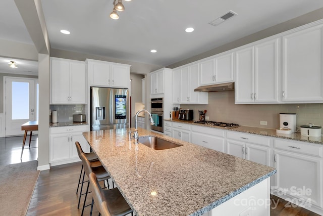 kitchen featuring stainless steel appliances, an island with sink, sink, and white cabinets