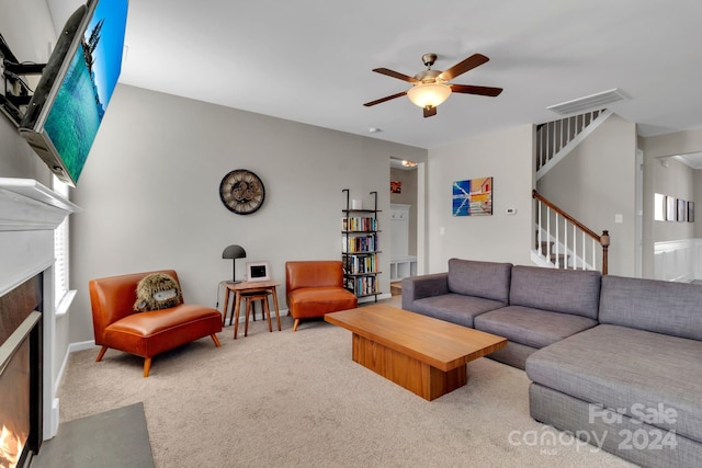 carpeted living room with a fireplace and ceiling fan