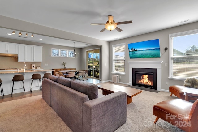 living room featuring light carpet, sink, and ceiling fan