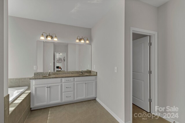 bathroom with tiled bath, tile patterned flooring, and dual bowl vanity