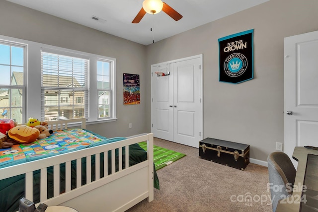 carpeted bedroom featuring ceiling fan and a closet