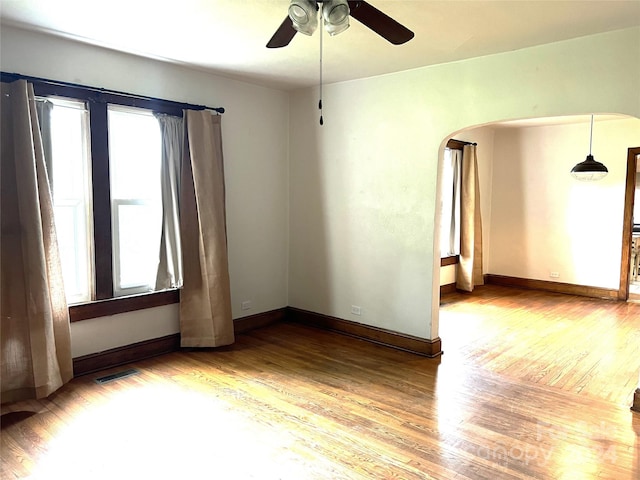 spare room featuring wood-type flooring, plenty of natural light, and ceiling fan