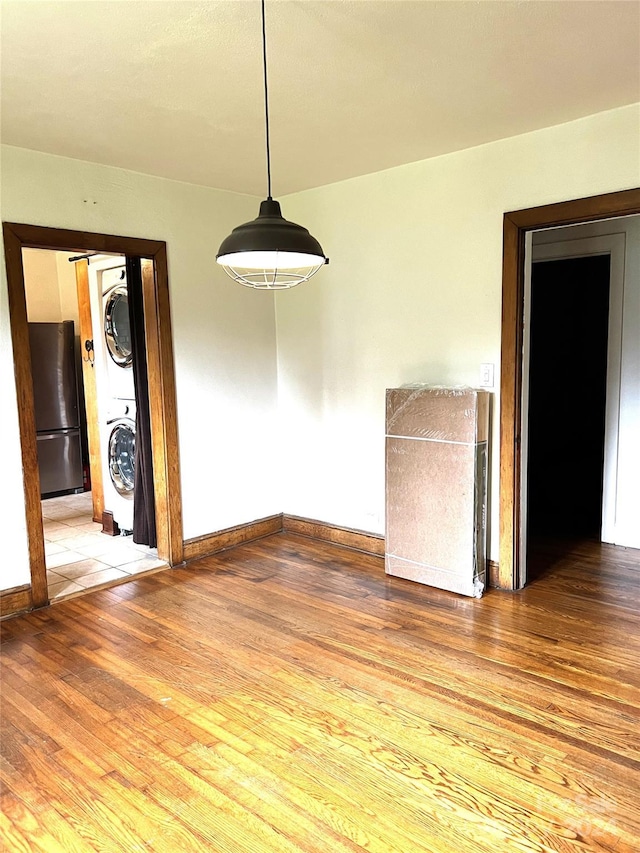 unfurnished dining area featuring stacked washer and dryer and hardwood / wood-style floors