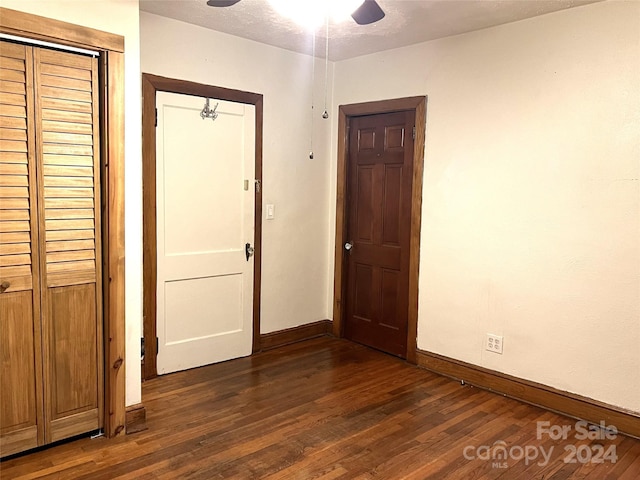 unfurnished bedroom with dark wood-type flooring, a textured ceiling, ceiling fan, and a closet