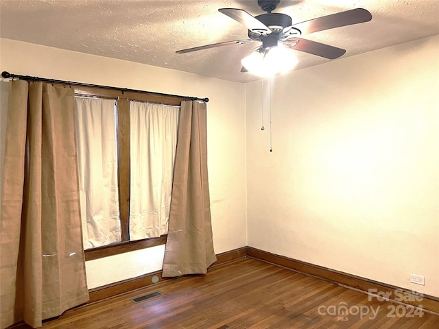 empty room with hardwood / wood-style floors and a textured ceiling