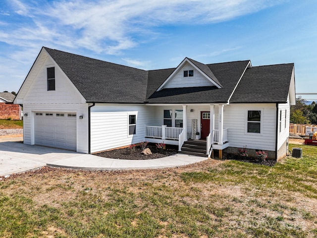 view of front of home with covered porch, a garage, a front lawn, and central AC unit