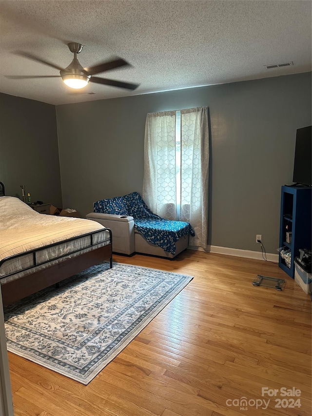 bedroom with ceiling fan, a textured ceiling, and light wood-type flooring