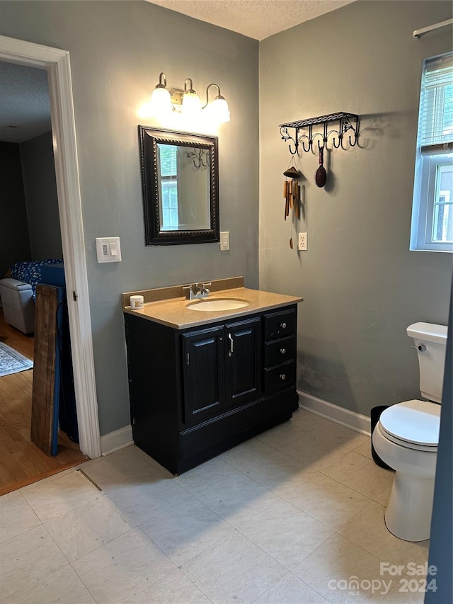 bathroom with toilet, tile patterned flooring, a textured ceiling, and vanity