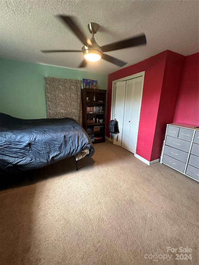 bedroom featuring ceiling fan, a textured ceiling, a closet, and carpet flooring