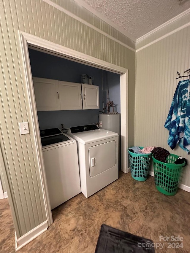 washroom featuring a textured ceiling, washer and clothes dryer, water heater, cabinets, and wood walls