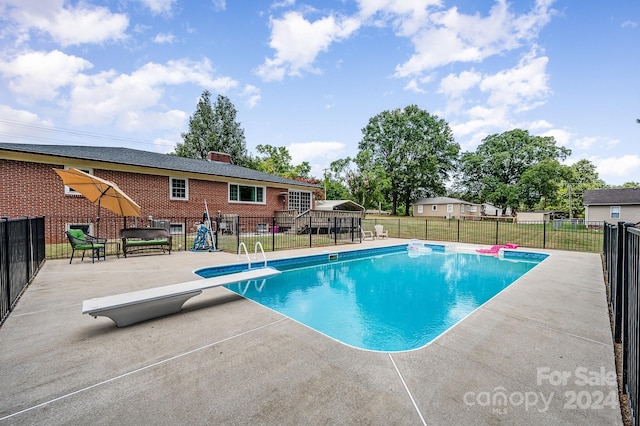 view of swimming pool with a diving board and a patio