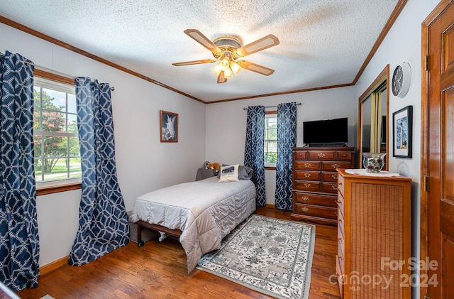 bedroom featuring ceiling fan, multiple windows, wood-type flooring, and a textured ceiling