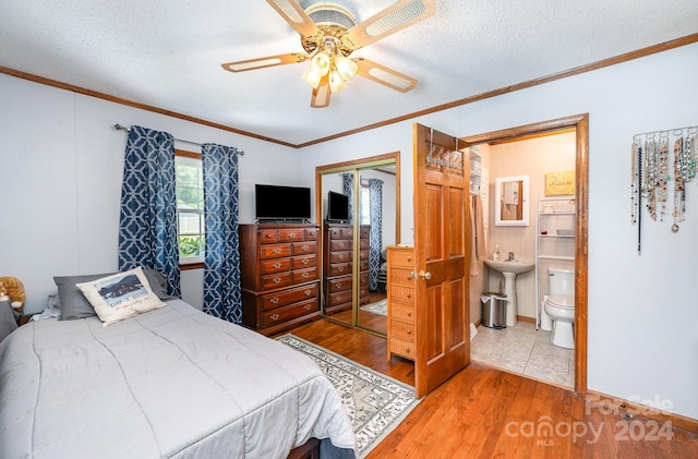 bedroom with ceiling fan, a closet, wood-type flooring, a textured ceiling, and crown molding