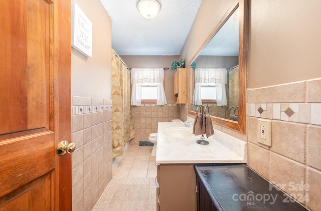 bathroom featuring toilet, tile patterned flooring, tile walls, and vanity