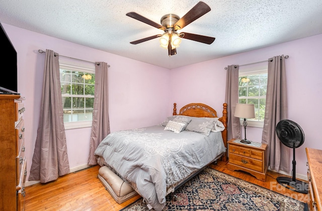 bedroom featuring ceiling fan, a textured ceiling, and light hardwood / wood-style floors