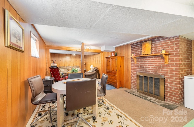 carpeted dining space with a textured ceiling, a brick fireplace, and wood walls