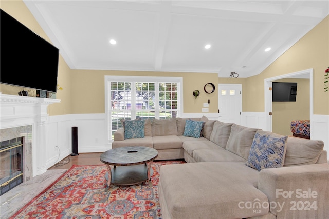 living room with light hardwood / wood-style floors, vaulted ceiling with beams, and a fireplace