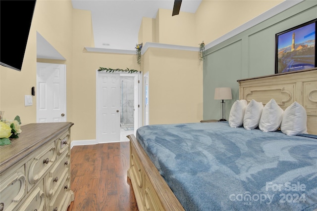 bedroom featuring ceiling fan, dark wood-type flooring, ensuite bath, and a towering ceiling