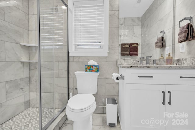 bathroom featuring toilet, tile walls, a shower with shower door, and vanity